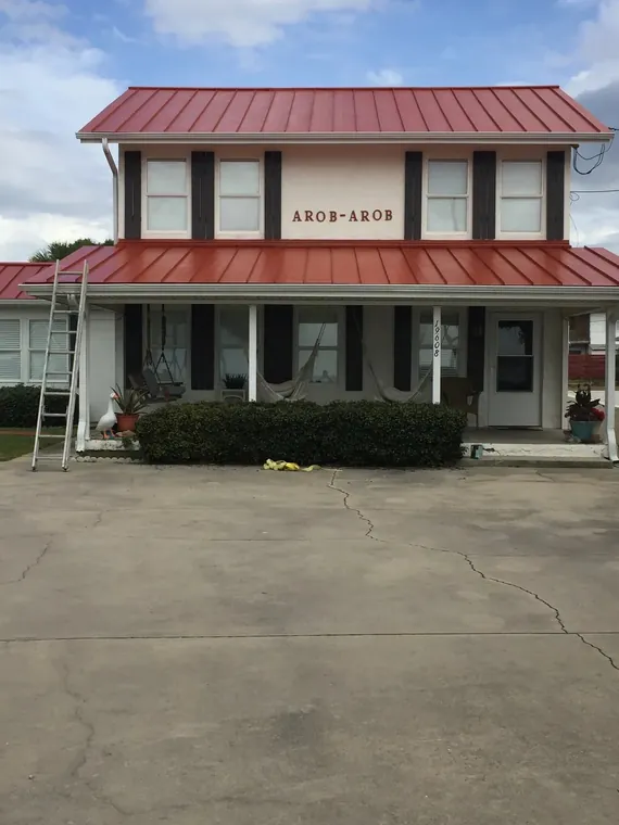 Exterior repaint of a two-story home with a red metal roof
