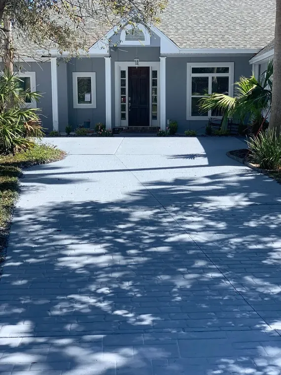 Gray home exterior repaint with a sealed decorative paver driveway