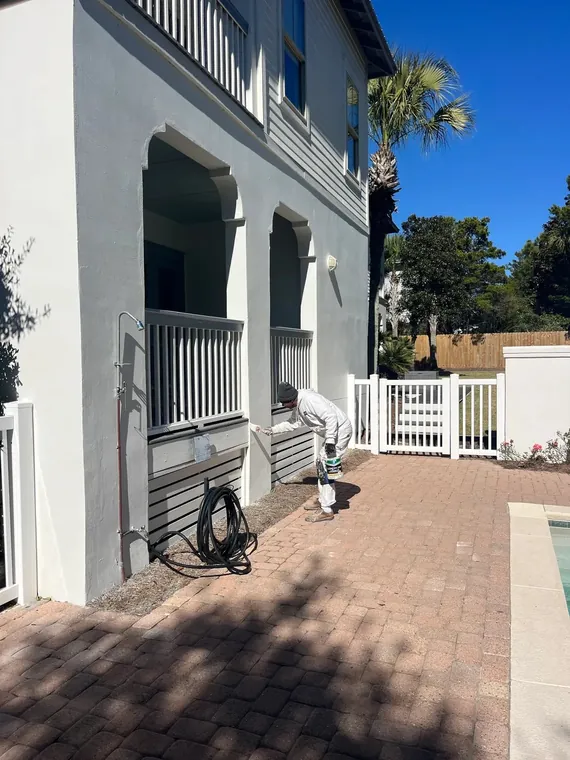 Spray-applied exterior repaint of a coastal home beside the pool